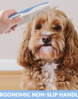 Hand holds a blue and white comb above a small curly brown dog with banner text that reads Ergonomic Non Slip Handle.