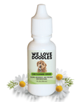 White 1 oz dropper bottle labeled We Love Doodles Ear Cleaning Serum with a doodle dog image and green label. Chamomile daisies sit around the bottle on a white background.