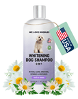 Bottle of Whitening Dog Shampoo 5-in-1 with a silver cap and a small white dog on the label. A green hang tag reads Made in USA. White daisies decorate the base on a clean white background.