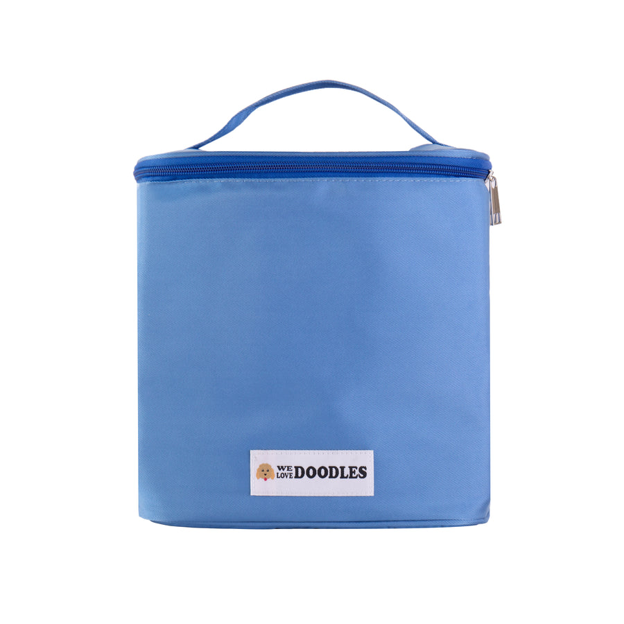 Light blue soft sided grooming bag shown upright and closed. A top carry handle and full zip lid are visible with a small We Love Doodles logo patch on the front