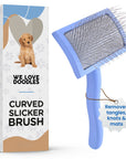 Blue curved dog slicker brush with angled pins positioned next to branded packaging. A hanging tag states removes tangles, knots and mats.