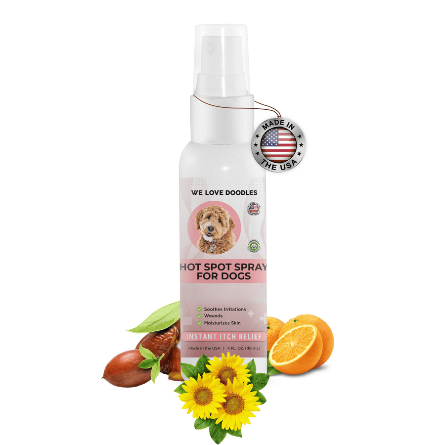 White 4 fl oz spray bottle labeled Hot Spot Spray for Dogs with a Made in the USA tag. Jojoba seeds, sunflower blooms, grapefruit, and grape seed oil sit around the bottle.