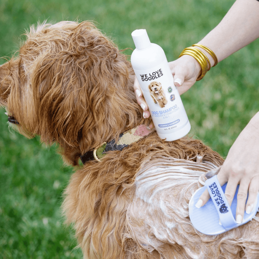 Single white 16 oz bottle labeled We Love Doodles 4-in-1 lavender and chamomile on a table with a soft tan coat in the background.