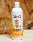 Single 16 oz Mango dog shampoo bottle standing on a cream surface with shaggy brown fur in the background. Label states Detangler and Conditioner 4 in 1.