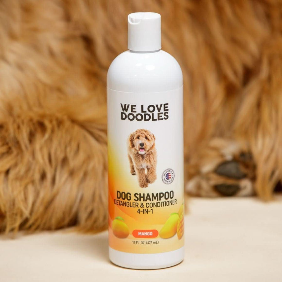 Single 16 oz Mango dog shampoo bottle standing on a cream surface with shaggy brown fur in the background. Label states Detangler and Conditioner 4 in 1.