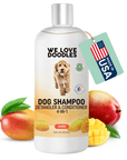 White 16 oz bottle with silver cap labeled We Love Doodles Dog Shampoo 4 in 1 mango. A green hang tag shows a USA flag. Whole and sliced mangoes with leaves sit around the base on a white background.