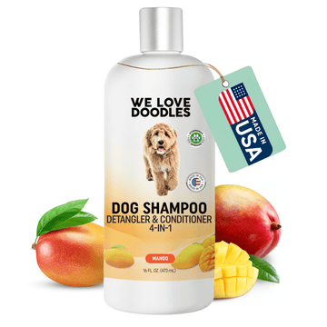 White 16 oz bottle with silver cap labeled We Love Doodles Dog Shampoo 4 in 1 mango. A green hang tag shows a USA flag. Whole and sliced mangoes with leaves sit around the base on a white background.