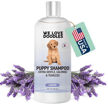 White 8 fl oz bottle labeled Puppy Shampoo extra gentle calming and tearless with a puppy on the label. Lavender sprigs surround the bottle and a green tag reads Made in USA.