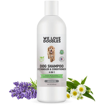 White bottle of We Love Doodles dog shampoo detangler and conditioner 4 in 1 unscented 16 fl oz with a doodle dog image and organic ingredient badges. Lavender and chamomile flowers sit at the base on a clean white background.