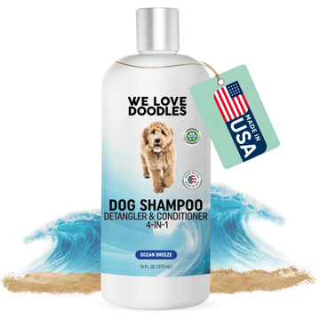 White 16 ounce bottle labeled Dog Shampoo 4 in 1 Detangler and Conditioner Ocean Breeze with blue wave art, sand, and a Made in USA tag.
