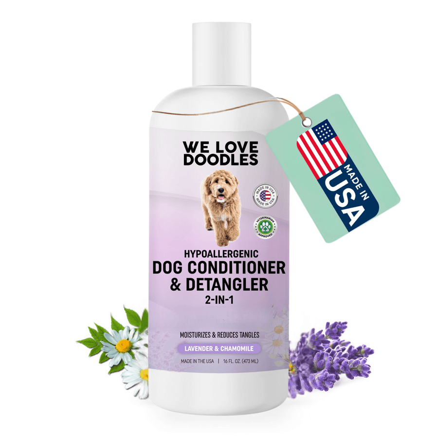White 16 fl oz bottle with a purple label that reads dog conditioner and detangler 2 in 1. Lavender and chamomile flowers sit near the base and a Made in USA tag hangs from the neck.
