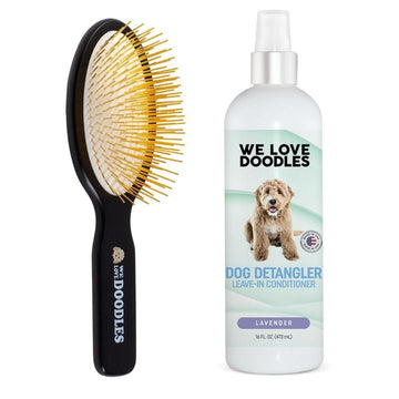 Black beechwood pin brush with gold pins next to a white 16 fl oz We Love Doodles lavender dog detangler leave in conditioner on a clean white background.