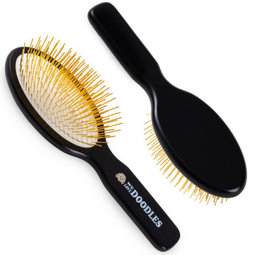 Black oval pin brush shown from front and back on a white background. Gold colored pins and a smooth black beechwood handle with logo are visible.
